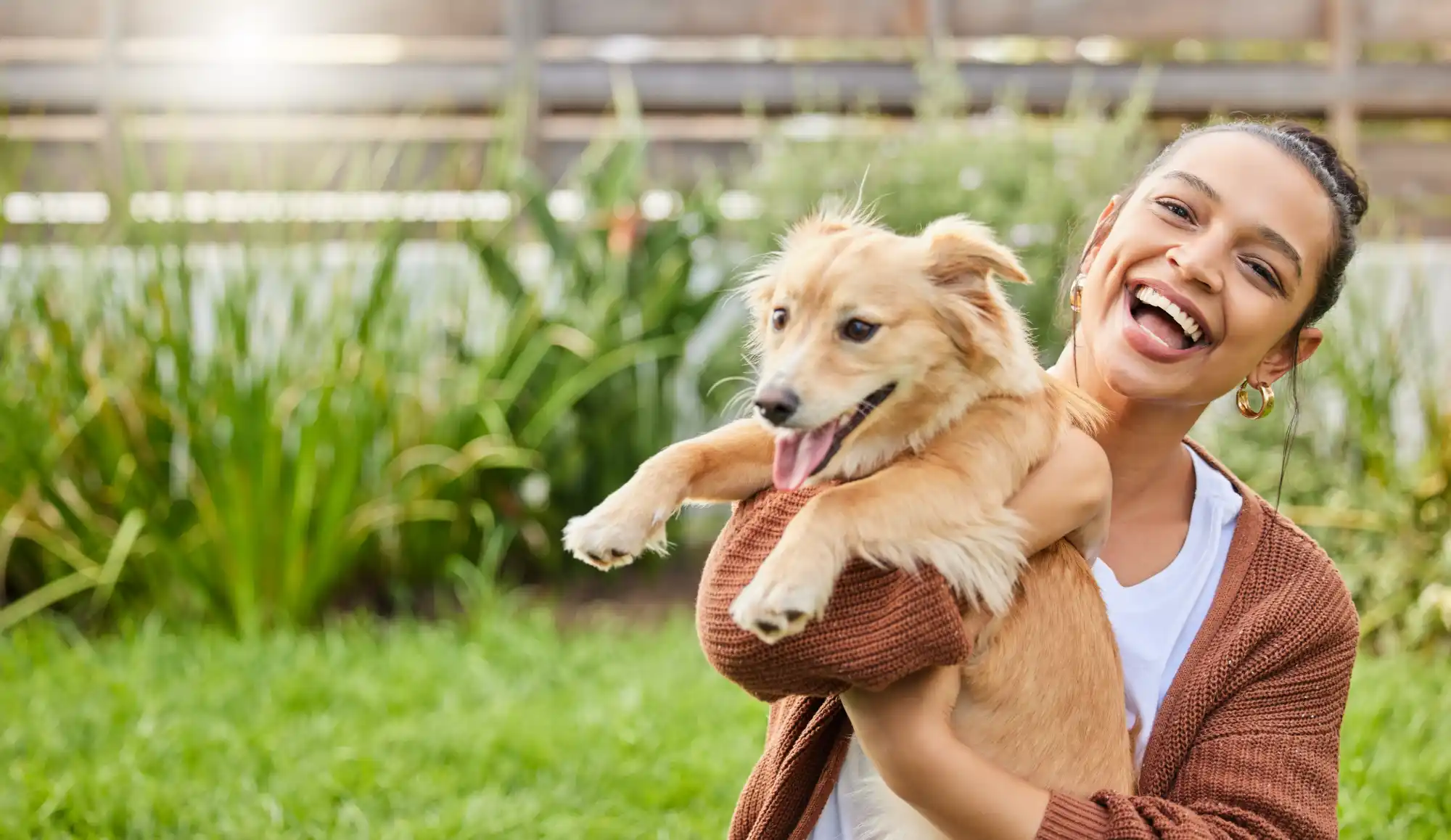 Smiling Chicago dog owner holding her happy dog in a clean backyard